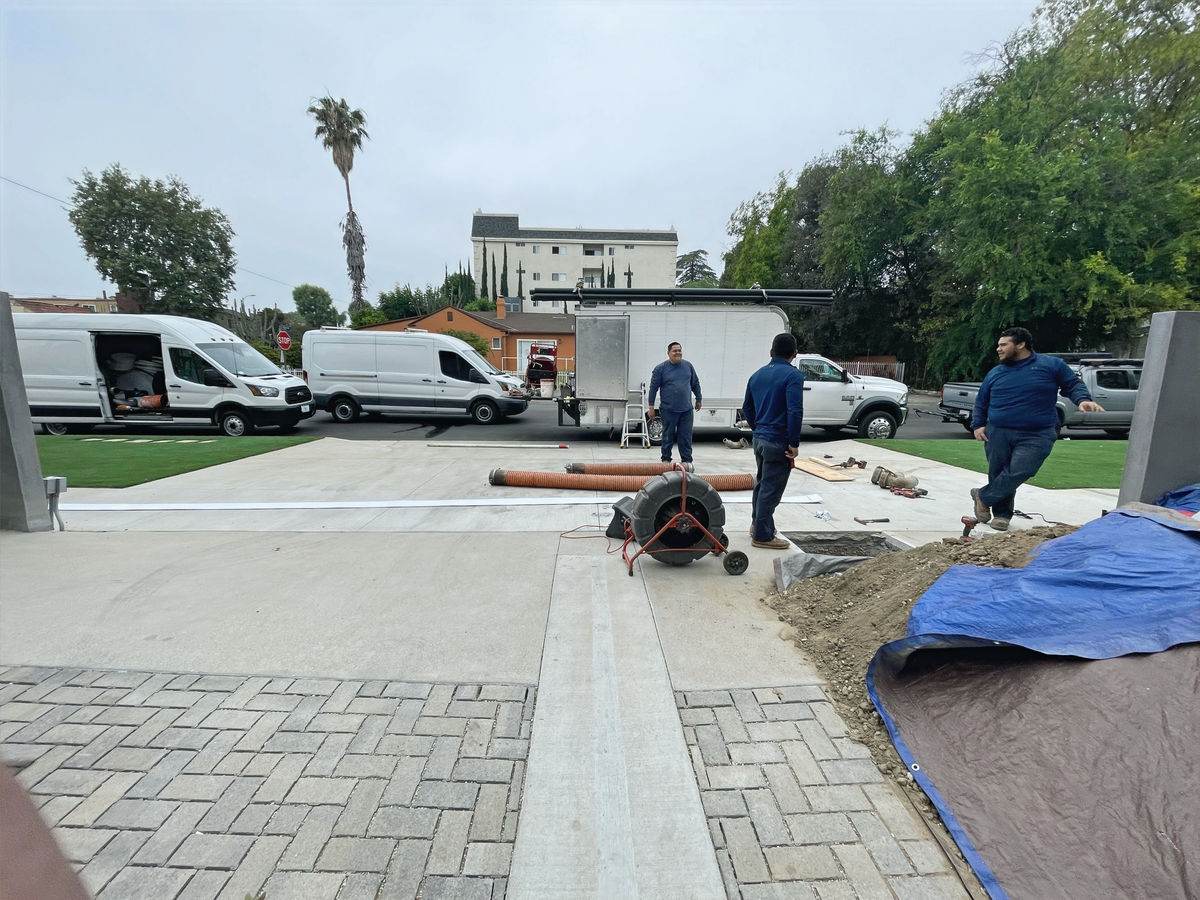 FastFlow sewer crew at a job site with orange sewer pipe and service vans